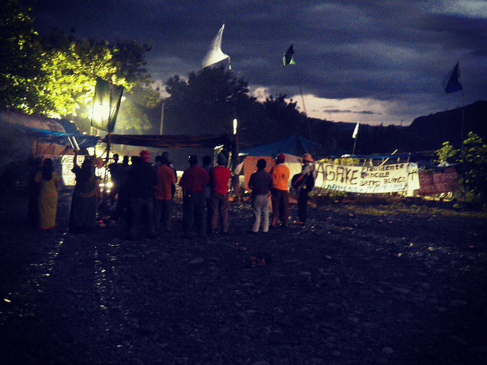 Days before their eviction from the site entrance, M22 gather for prayers under police spotlights. (Photo: Oscar Sogandares)