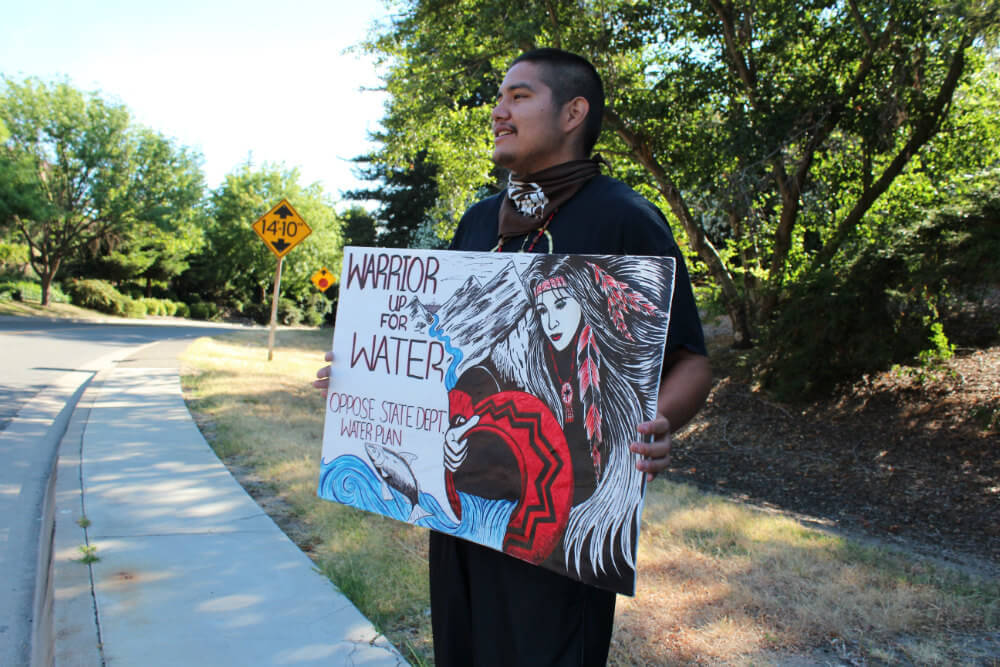 Gerald Thomas, Elem Pomo, holds up a sign proclaiming, "Warrior Up For Water." Photo by Dan Bacher.