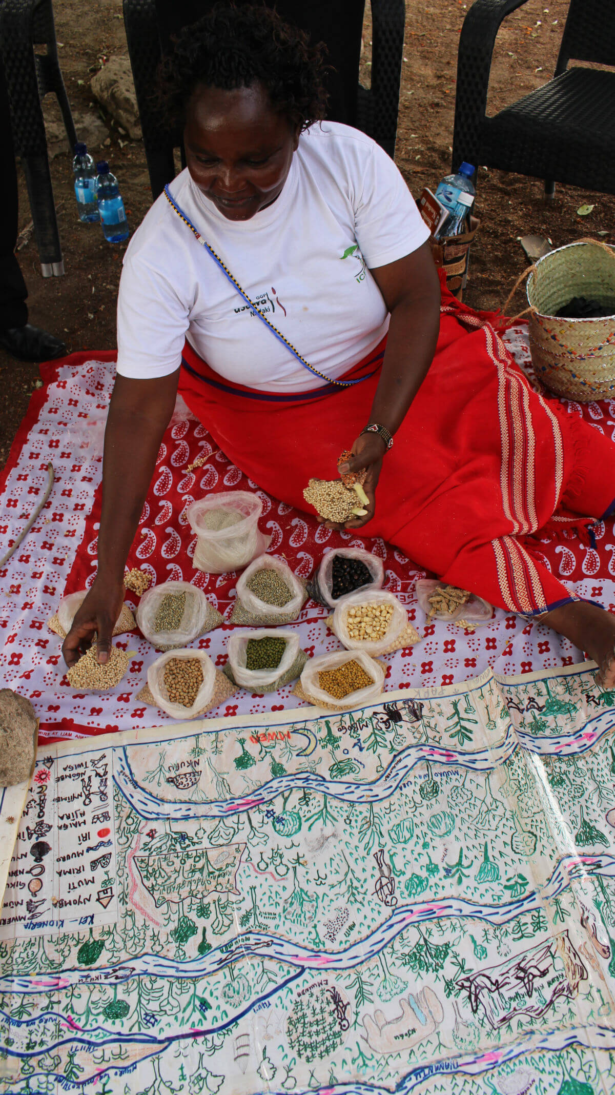 Sabella Kaguna, a sacred site custodiand from Tharaka, Kenya, with a map of her ancestral territory and indigenous seeds w1200