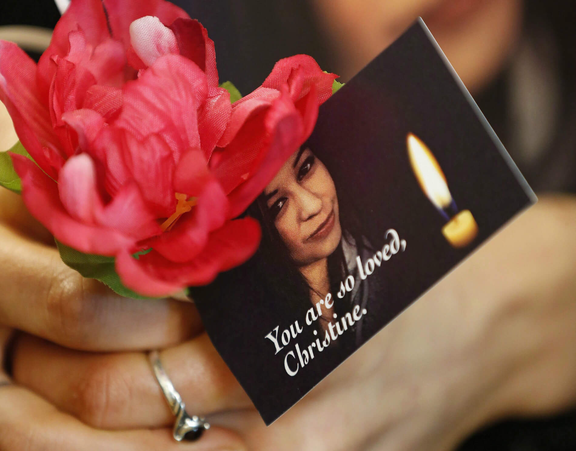 woman holds a flower and a photo of Christine Wood